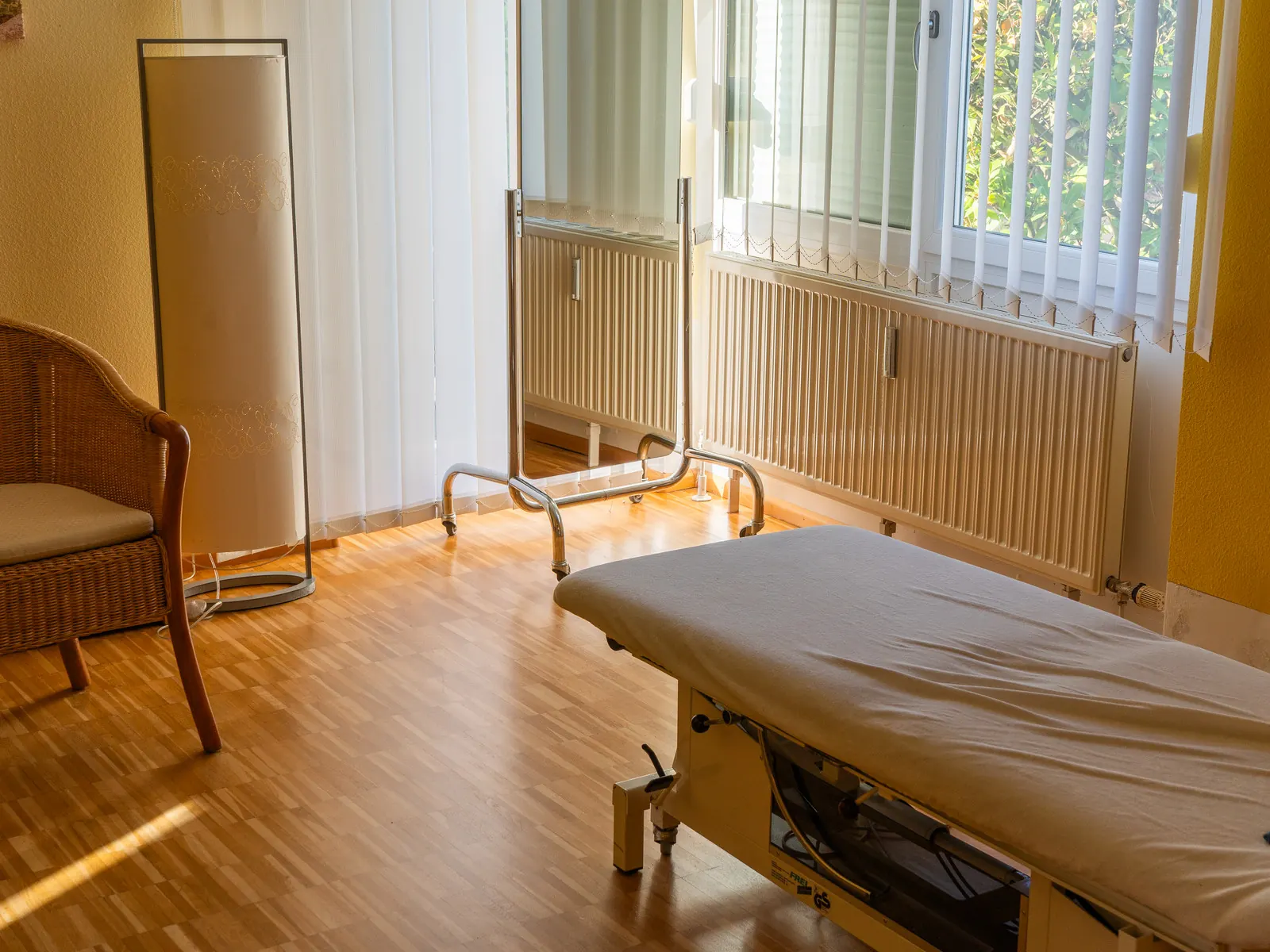 Behandlungsliege am Fenster, Nachmittagslicht auf dem Parkett