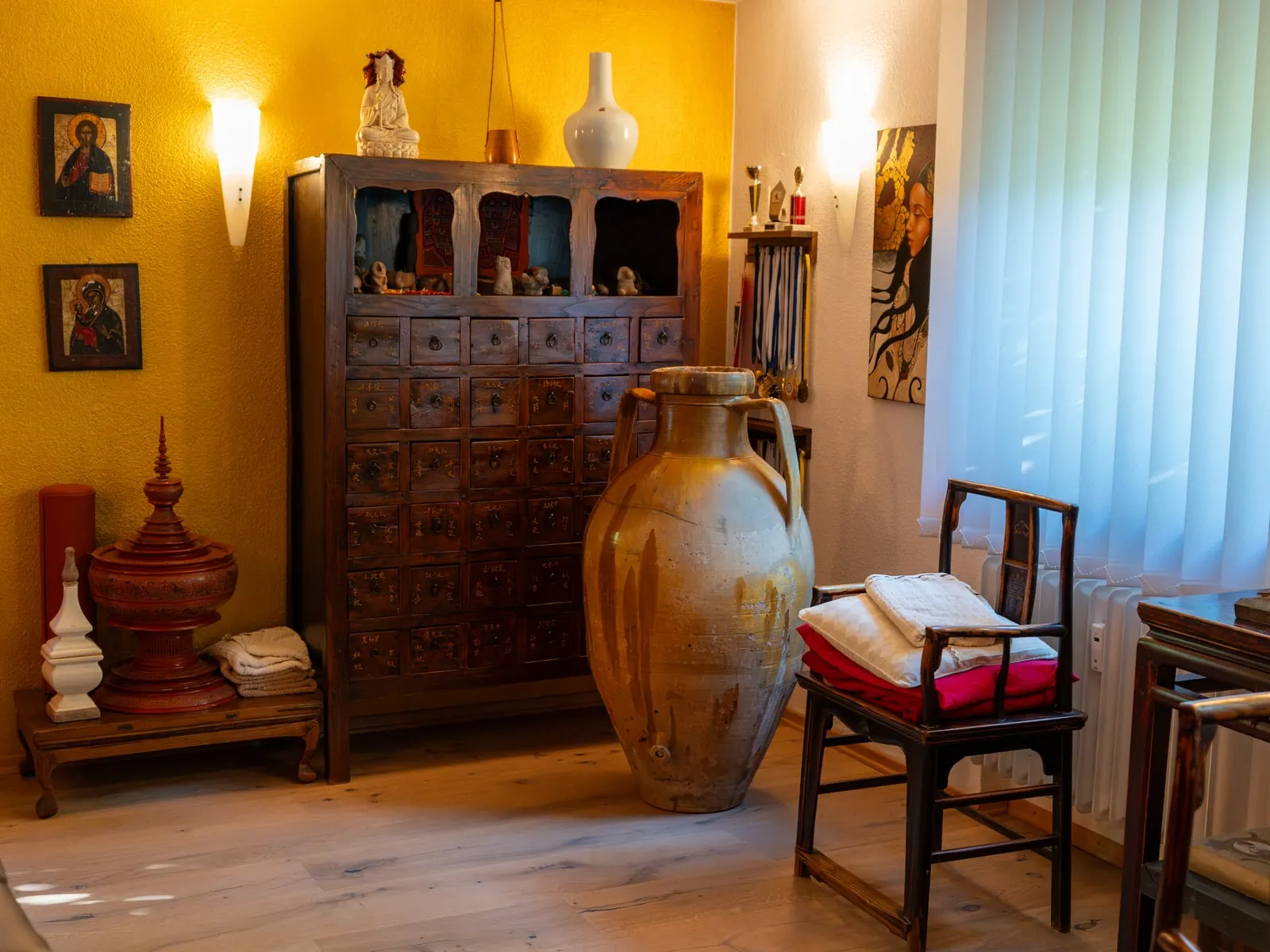 Alter Apothekerschrank mit Tonkrug und Stuhl am Fenster