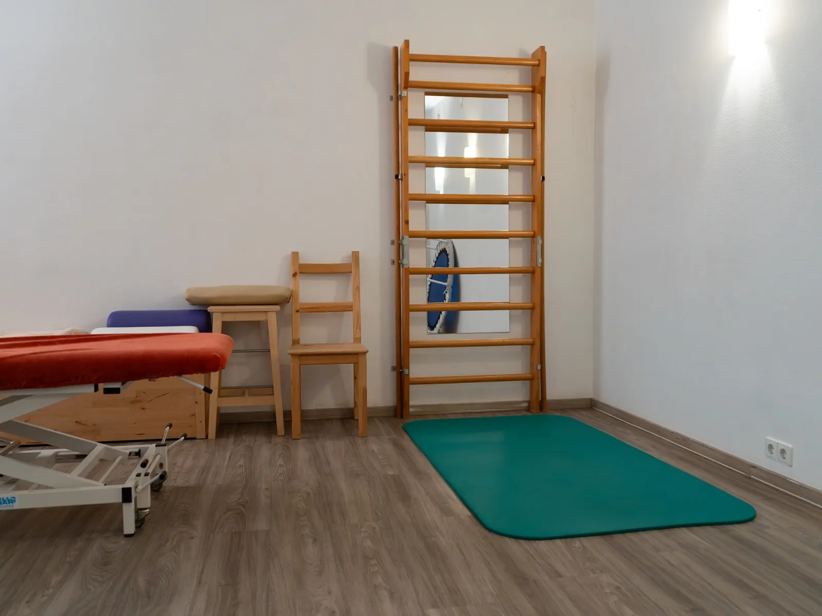 Übungsbereich mit Sprossenwand, Gymnastikmatte und Behandlungsliege
